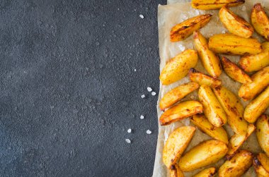 Kızarmış altın baharatlı patates dilimleri ya da karanlık masada pişmiş fırın. Köy tarzında lezzetli, lezzetli, çıtır çıtır atıştırmalıklar. Üst görünüm.