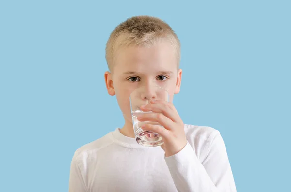 Schattig kind dat schoon water drinkt uit glas. Blond jongetje met waterglas, kijkend naar de camera. — Stockfoto