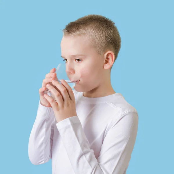 Słodkie dziecko pijące czystą wodę ze szkła. Blond mały chłopiec z szklanką wody. — Zdjęcie stockowe