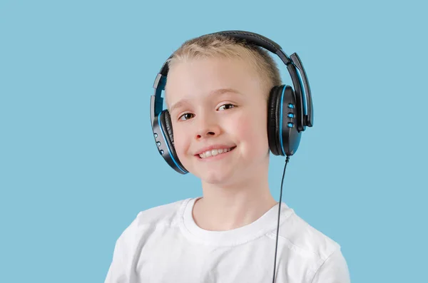 Feliz niño escuchando música con auriculares y mirando a la cámara. Retrato del niño de la escuela en auriculares . — Foto de Stock