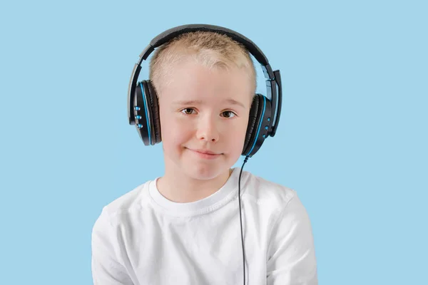 Feliz niño escuchando música con auriculares y mirando a la cámara. Retrato del niño de la escuela en auriculares . — Foto de Stock
