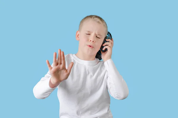 Młode dziecko trzymaj rękę na słuchawkach, słuchając muzyki i śpiewając. Nastolatek ze słuchawkami. — Zdjęcie stockowe