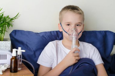 Hasta çocuk astım maskesi ile nefes alıyor. Koronavirüs, astım ve alerji gibi solunum hastalıklarının önlenmesi için nebulizör ve sprey kullanımı. Evde terapi..