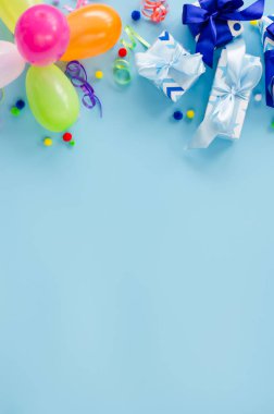 Parti ya da doğum günü mavi arka planı. Tatil maketi. Kopya alanı olan tebrik kartı. Renkli balon, hediye kutuları ve yılan yağıyla çerçevelenmiş. Üst Manzara. Düz yatıyordu.
