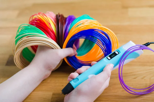 Çocuğun elleri, ABS plastiğini sargılar ve 3 boyutlu kalemle tutuyor. El yapımı. BTMM eğitimi. Yeni teknoloji. Okuldan sonra hobi.