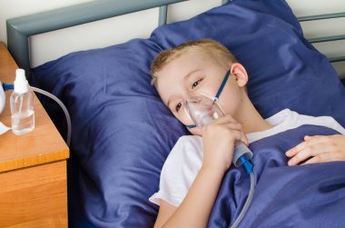 Hasta çocuk astım maskesi ile nefes alıyor. Koronavirüs, astım ve alerji gibi solunum hastalıklarının önlenmesi için nebulizör ve sprey kullanımı. Evde terapi..