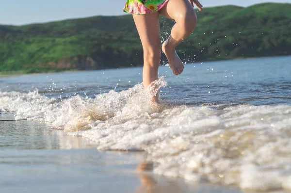 青い海で水しぶきビーチの海岸を走っている少女 — ストック写真