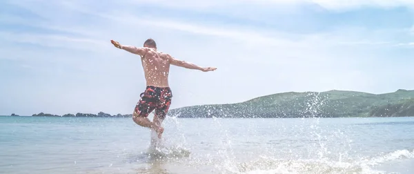 筋肉の若い男が、岸から海にダイブします。 — ストック写真