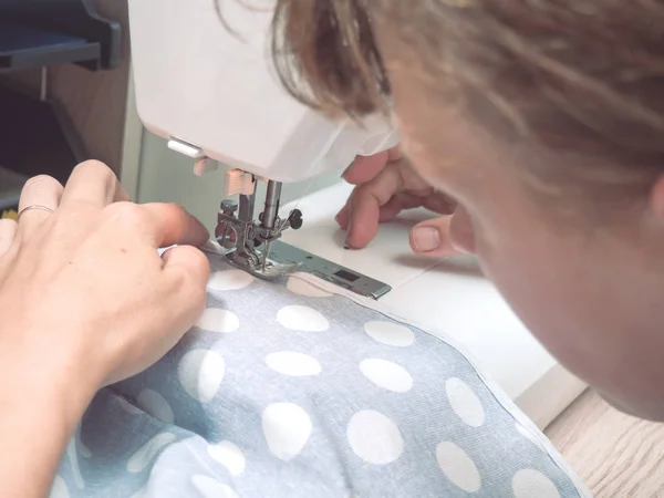 Female hands sew the blue fabric — Stock Photo, Image