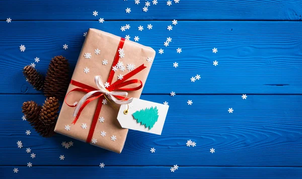 Різдвяний подарунок з червоною стрічкою на синьому фоні зі сніжинками — стокове фото