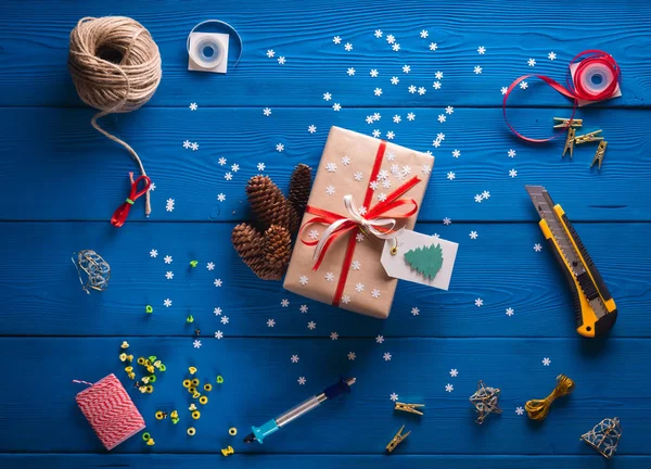 Libro de recortes. Embalaje de un regalo de Navidad en papel kraft sobre un fondo de madera azul — Foto de Stock