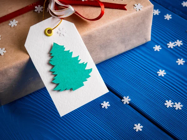 Etiqueta branca com a imagem de abeto de Natal em um presente com uma fita vermelha — Fotografia de Stock