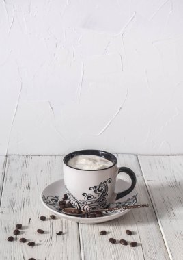 sabah krem, kahve çekirdekleri ve ahşap bir masa üzerinde bir kaşık ile kahve bir fincan