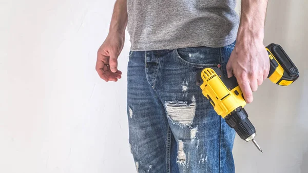 Hand electric tool: a yellow electric screwdriver in the hands