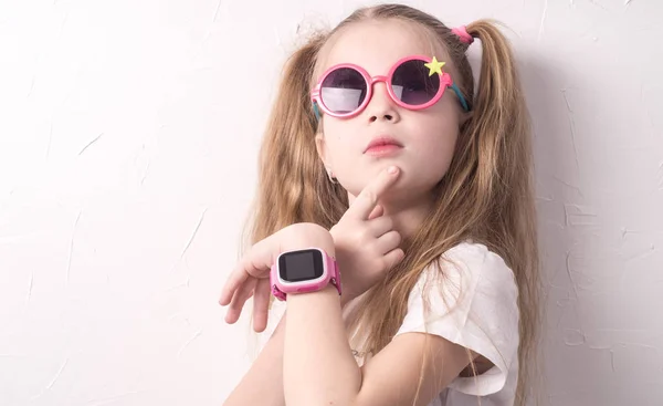 Çocuklar için teknoloji: pembe gözlüklü bir kız bir smartwatch kullanır.