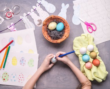 Paskalya kutlamaları için hazırlanıyor: kız Paskalya yortusu yumurta bir çizim yapar.