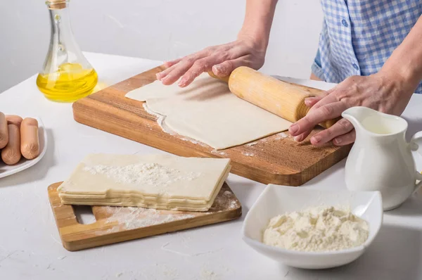 Home baking: a woman rolls the dough with a rolling pin.