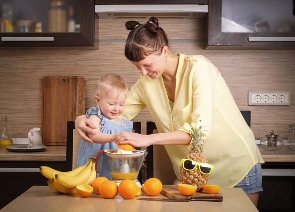 Healthy food for children: Mom and daughter make fresh orange juice