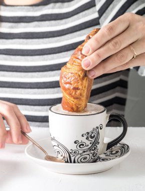 Bir kahve bir kruvasan daldırma bir el görünümünü yakın çekim