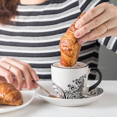 Bir kahve bir kruvasan daldırma bir el görünümünü yakın çekim