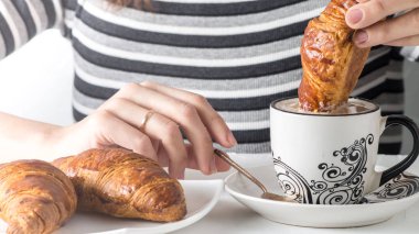 Bir kahve bir kruvasan daldırma bir el görünümünü yakın çekim