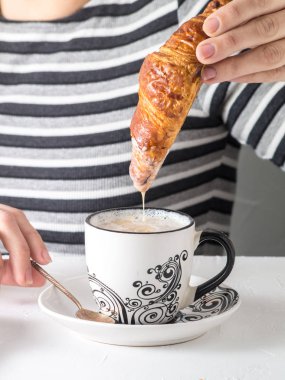 Bir kahve bir kruvasan daldırma bir el görünümünü yakın çekim