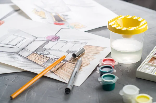 Δημιουργικό επάγγελμα: γραφείο του σχεδιαστή με διάσπαρτα σκίτσα, χρώματα, πινέλα, επένδυση, μολύβι. — Φωτογραφία Αρχείου