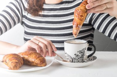 Bir kahve bir kruvasan daldırma bir el görünümünü yakın çekim