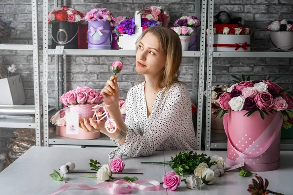 A girl collects a bouquet of roses in a box for the upcoming holiday.