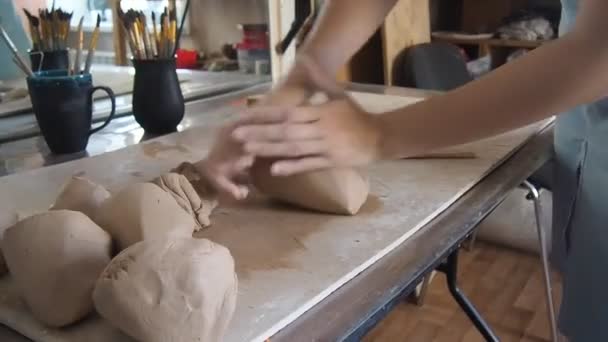 Una chica Potter amasa un pedazo de arcilla con sus manos en su taller de estudio . — Vídeos de Stock