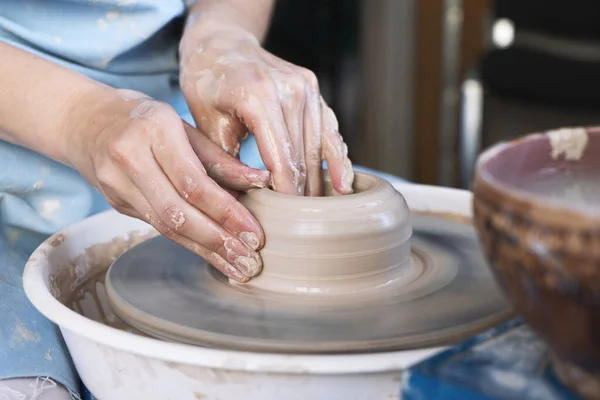 Meisje Potter beeldhouwt een kruik klei op een pottenbakkerswiel. — Stockfoto