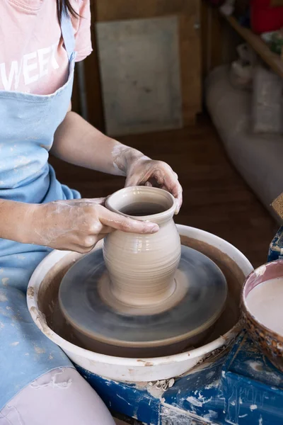 Meisje Potter beeldhouwt een kruik klei op een pottenbakkerswiel. — Stockfoto