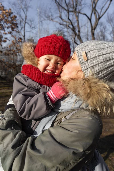 Mother and little daughter in warm hats in the autumn Park. — Stock Photo, Image