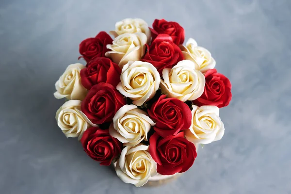 Flores en flor: Ramo de rosas rojas y blancas sobre un fondo gris . — Foto de Stock