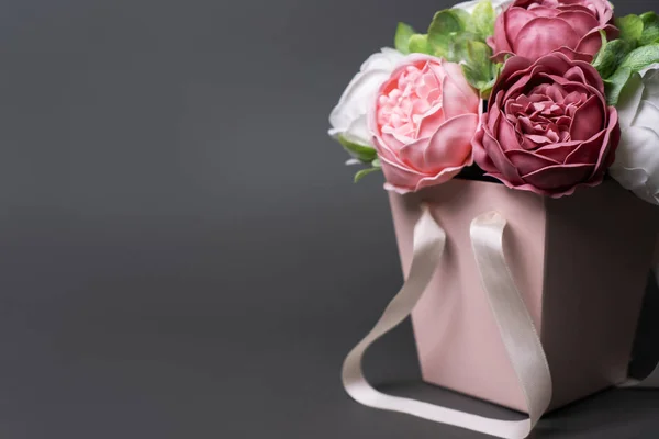 Flores en flor: Ramo de peonías lila y rosa en una caja cuadrada rosa sobre un fondo gris . — Foto de Stock