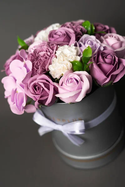 Flores en flor: Ramo de rosas lila y blanca en una caja redonda gris sobre un fondo gris . —  Fotos de Stock