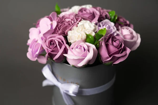 Цветущие цветы: букет сирени и белые розы в серой круглой коробке на сером фоне . — стоковое фото