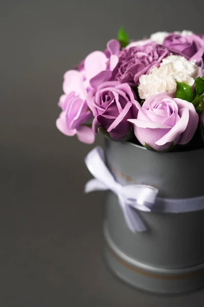 Flores en flor: Ramo de rosas lila y blanca en una caja redonda gris sobre un fondo gris . — Foto de Stock