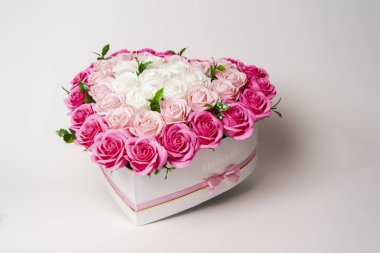 Çiçek açan çiçekler: Beyaz arkaplanda kalp şeklinde bir kutuda büyük bir buket pembe ve beyaz güller.