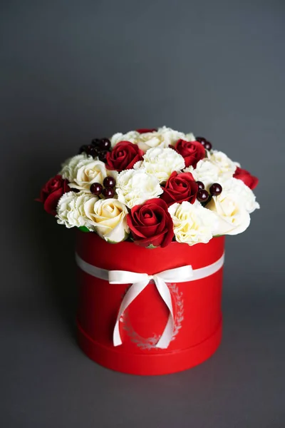 Цветы в цвете: букет красных и белых роз в красной круглой коробке на сером фоне . — стоковое фото