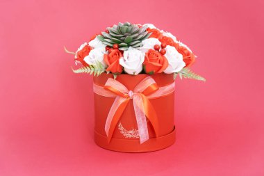 Çiçek açan çiçekler: Pembe arka planda kırmızı yuvarlak bir kutuda kırmızı ve beyaz güller..