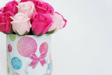 Çiçek açan çiçekler: Beyaz arka planda yuvarlak bir kutuda pembe ve beyaz güller buketi.