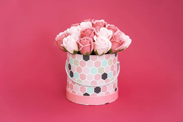 Flores en flor: Un ramo de rosas rosadas y blancas en una caja redonda sobre un fondo rosado . — Foto de Stock