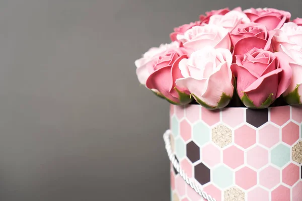 Flores en flor: Un ramo de rosas rosadas y blancas en una caja redonda sobre un fondo gris . — Foto de Stock