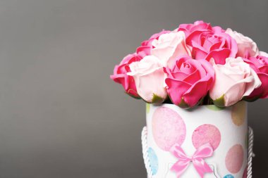 Çiçek açan çiçekler: Gri arka planda yuvarlak bir kutuda pembe ve beyaz güller buketi.