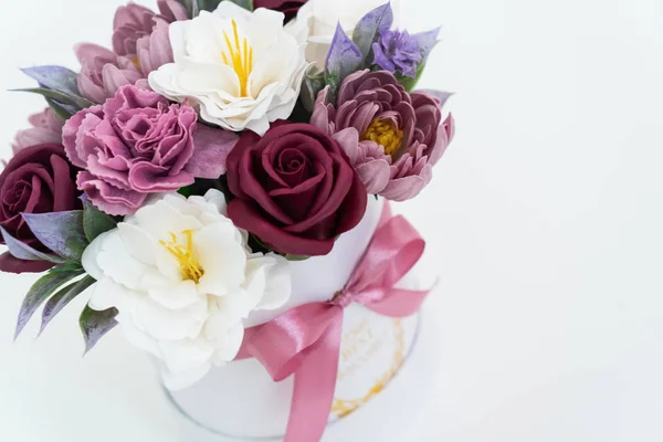 Flores en flor: cogollos rojos y rosados multicolores en una caja redonda blanca sobre un fondo blanco . — Foto de Stock