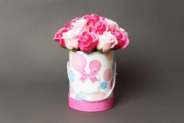 Flores en flor: Un ramo de rosas rosadas y blancas en una caja redonda sobre un fondo gris . — Foto de Stock