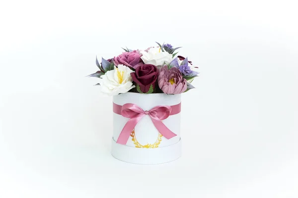 Blütenpracht: bunte rote und rosa Knospen in einer weißen runden Schachtel auf weißem Hintergrund. — Stockfoto