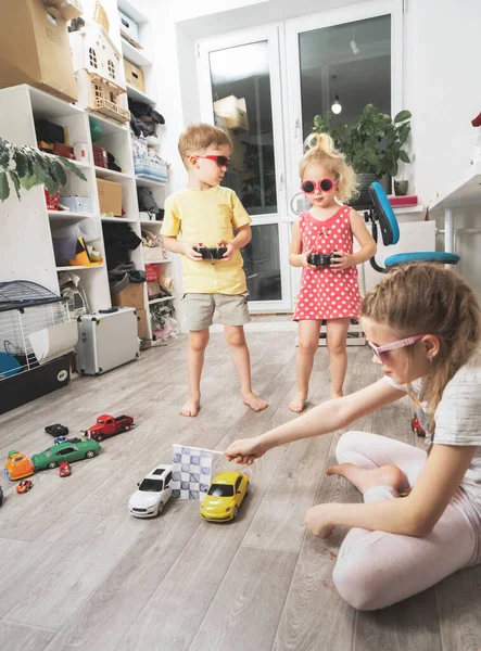 Passatempos infantis: Crianças brincam em casa com modelos de carros controlados por rádio e competições de corrida organizadas . — Fotografia de Stock