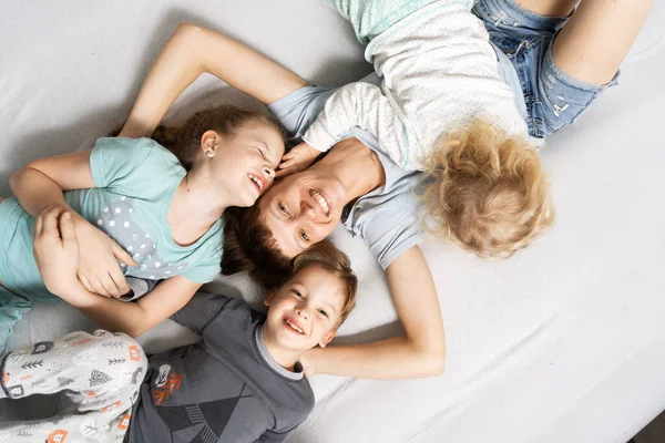 Famiglia Mamma Tre Bambini Sono Sdraiati Letto Bianco Abbracciati Ridendo — Foto Stock